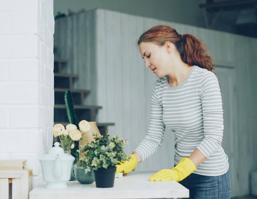 A cleaner in yellow gloves wiping down a table