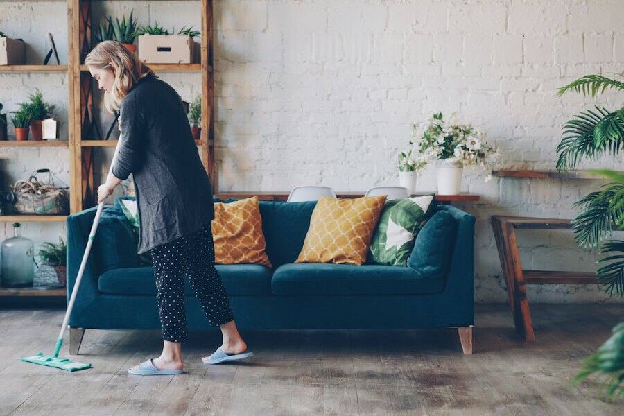 A cleaner mopping the floor of a bright living room